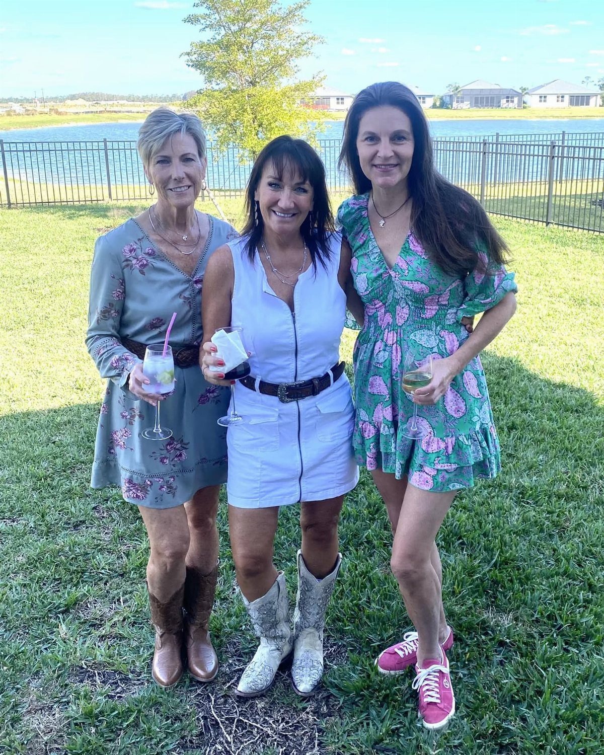 Three women posing outdoors wearing colorful mini dresses and various stylish footwear.