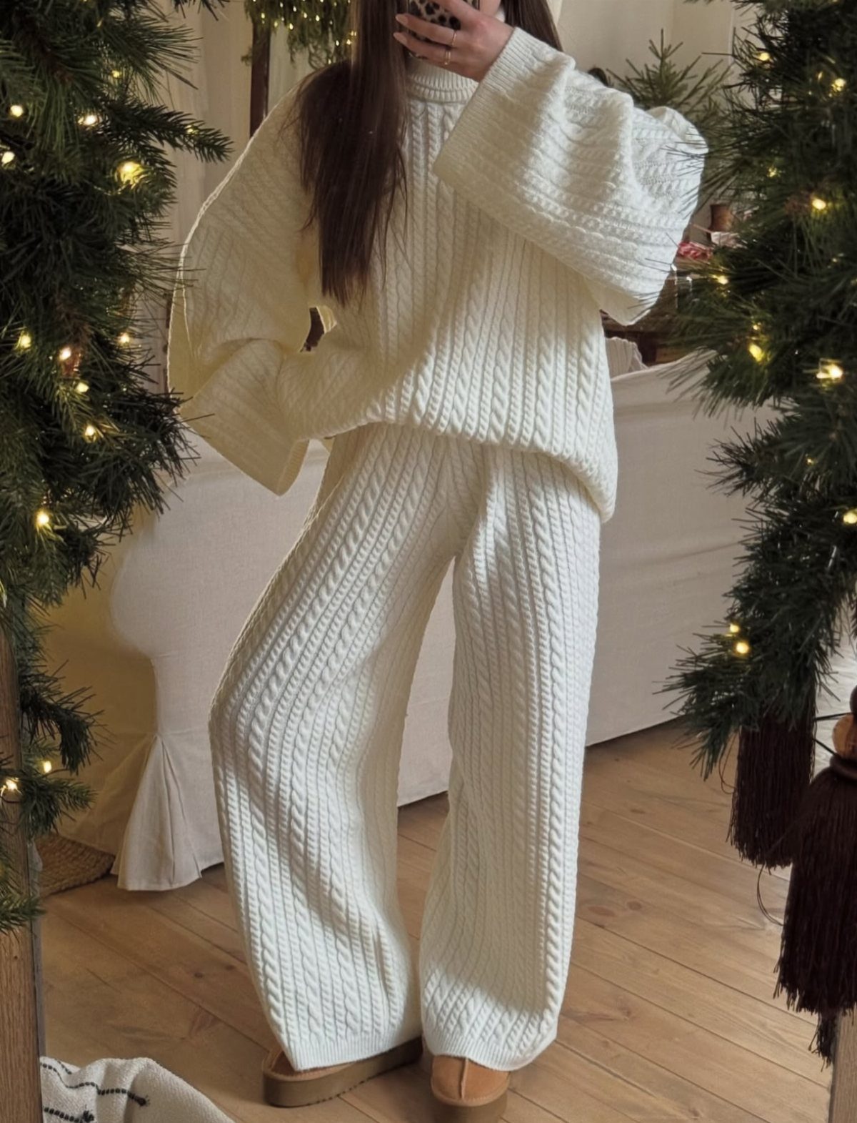 Person wearing a white cable-knit sweater and matching wide-leg knit pants indoors.