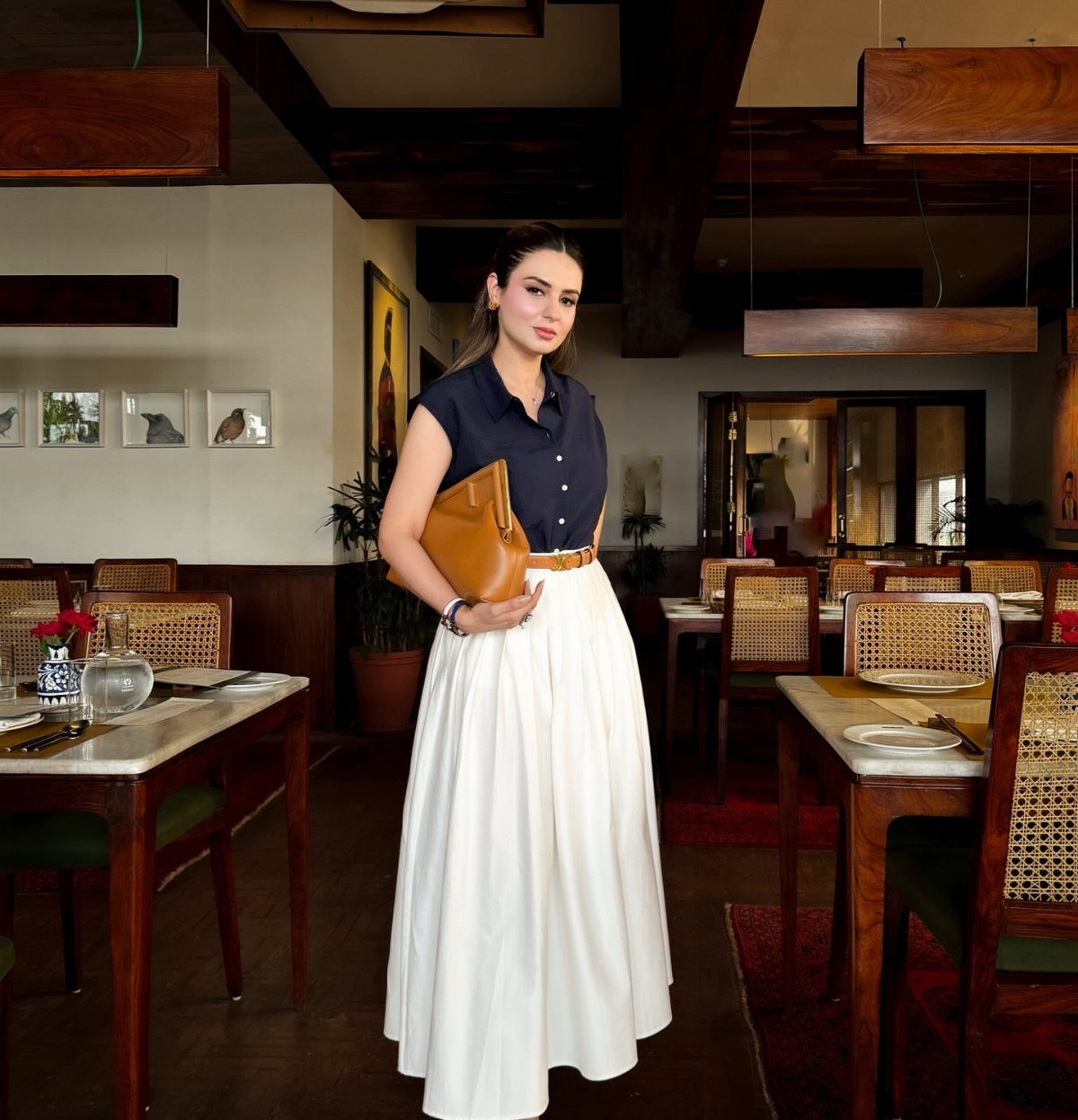 Woman wearing a navy button-down shirt and long white skirt in a restaurant