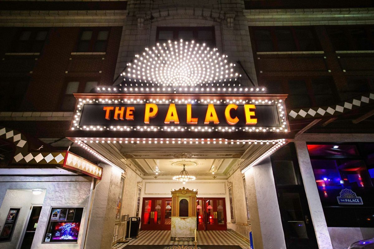 The Palace theater entrance with a glowing orange marquee and white lights at night.