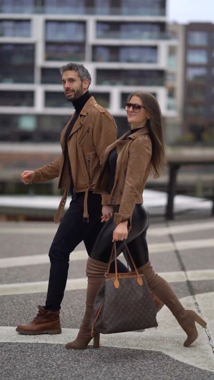 Couple walking in city wearing matching tan suede jackets and black outfits