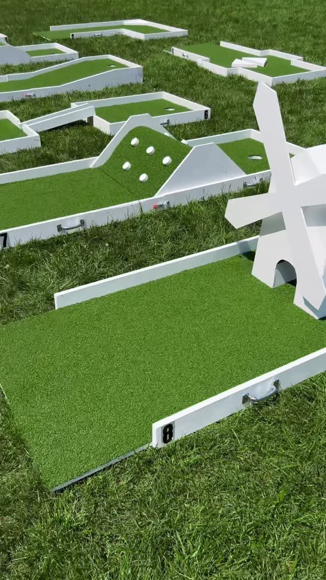 Portable mini golf holes with green turf and white frames on a grass lawn.