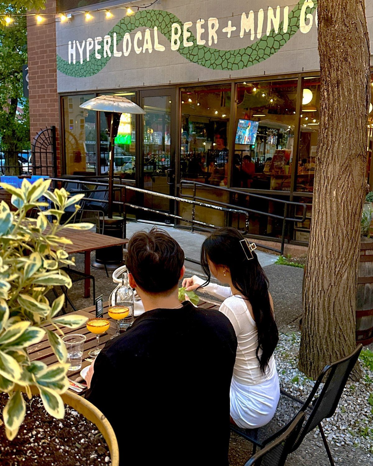 Couple sitting at an outdoor table in front of a mini golf venue.