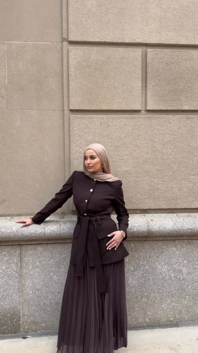 Woman in beige hijab, belted brown blazer, and pleated brown maxi skirt.