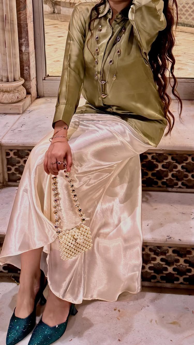 Olive green satin blouse and cream satin midi skirt with pearl handbag and heels.