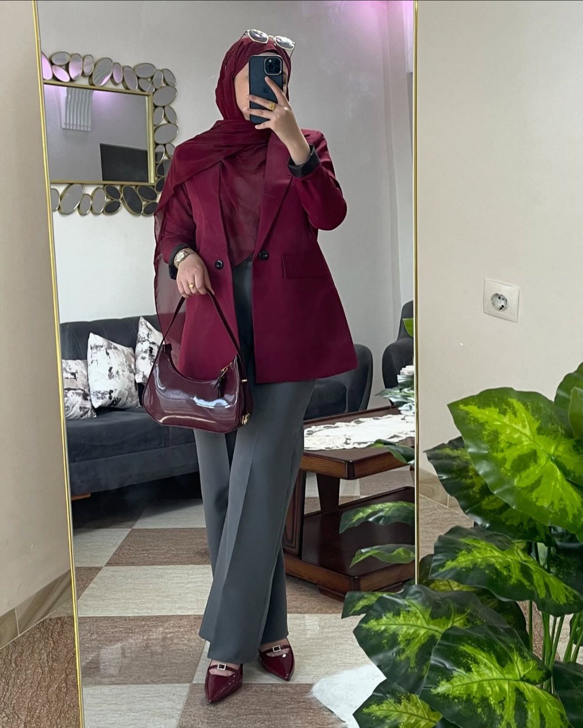 Woman in maroon blazer and grey wide-leg trousers posing for a mirror selfie.