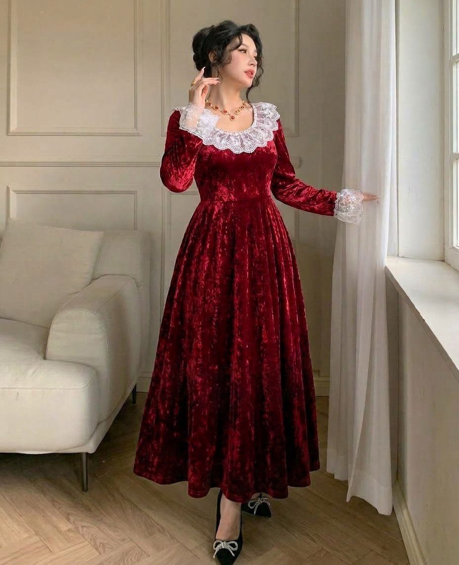 Woman in a red velvet midi dress with white lace collar and gold necklace.
