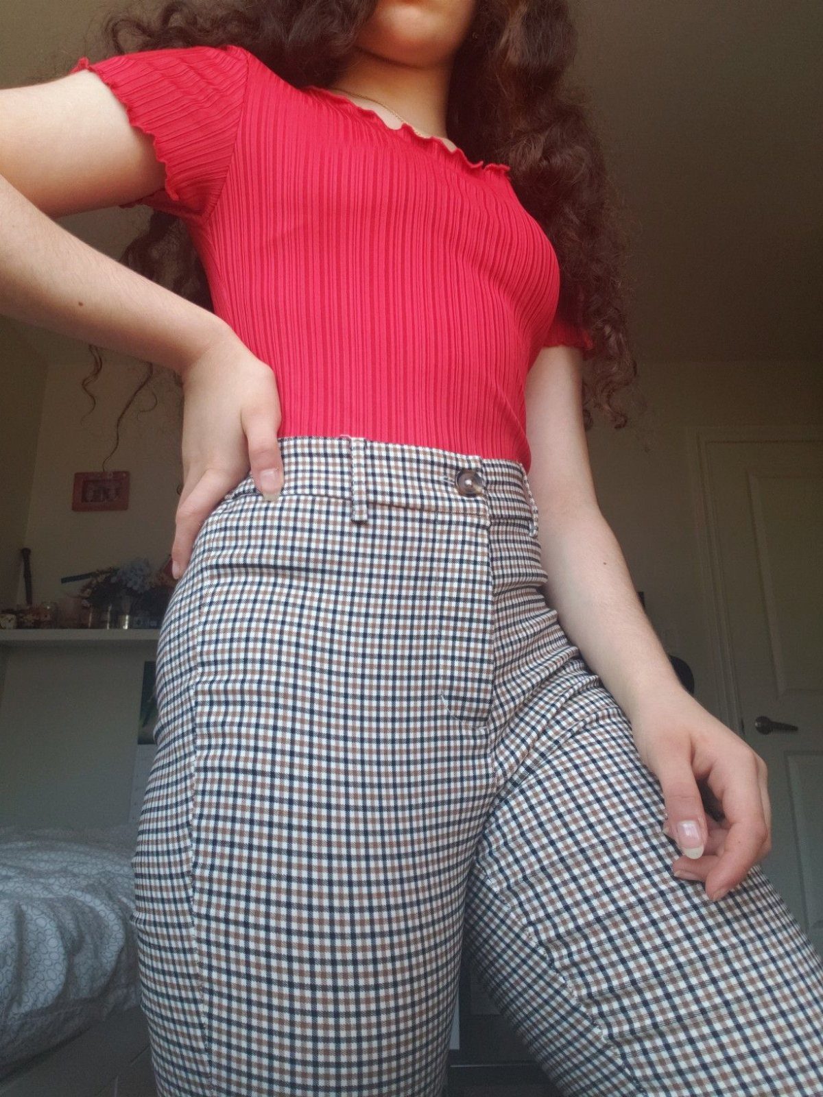 Person wearing a red ribbed crop top and black and white plaid pants.