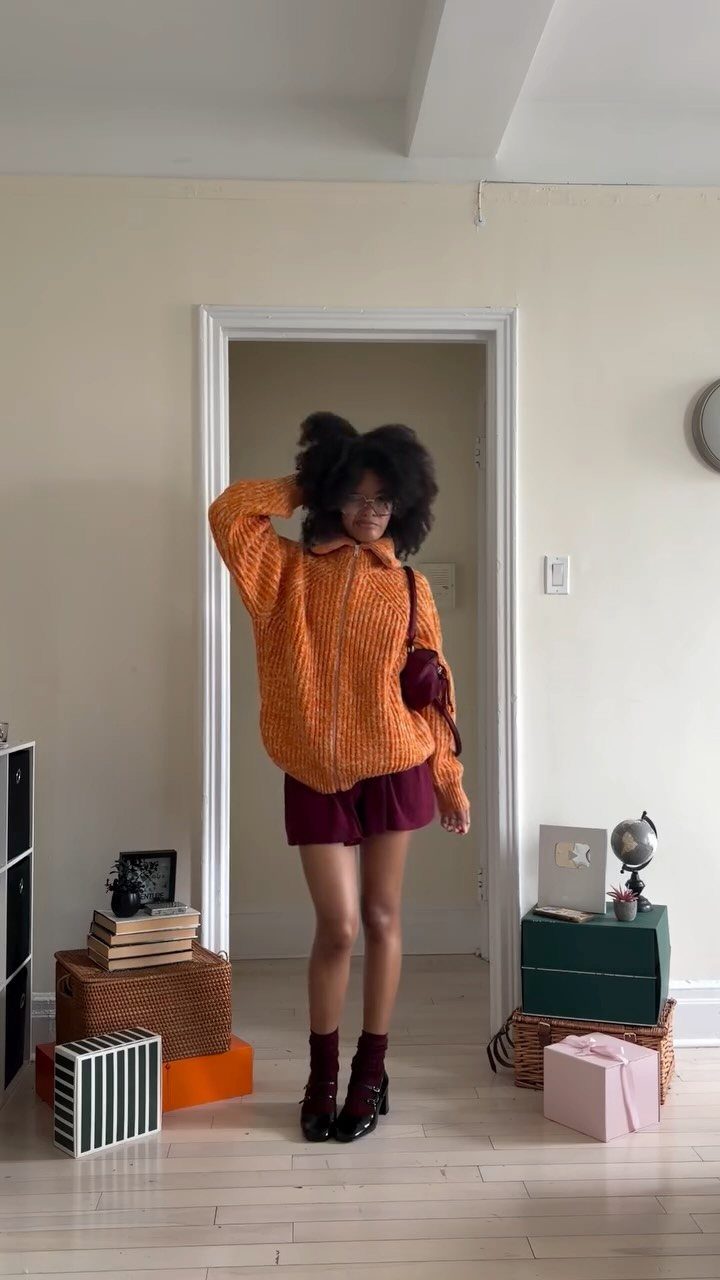 Person wearing an orange sweater and maroon skirt as a Velma costume.