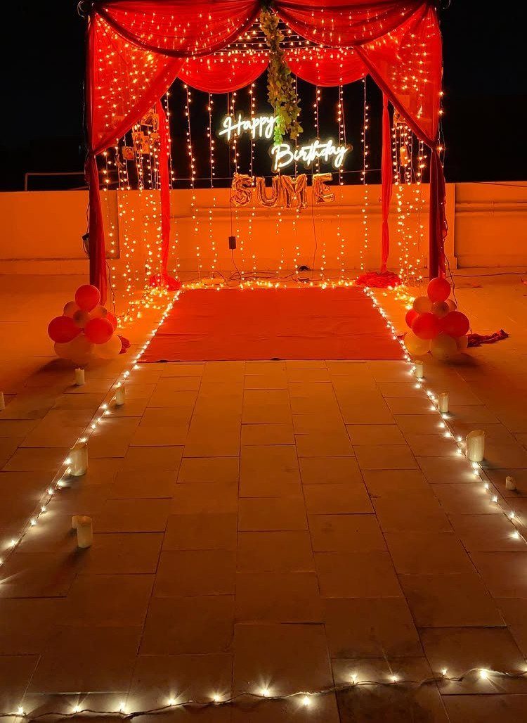 Red carpet walkway leading to a glowing birthday neon sign under a lit canopy.