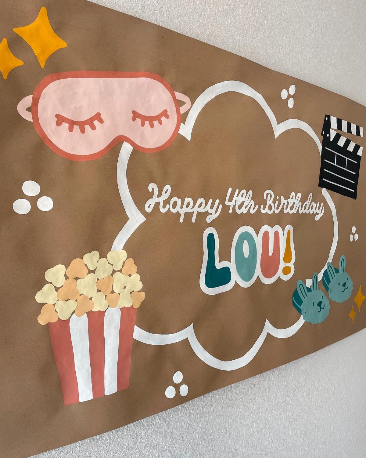 Brown birthday banner with movie-themed illustrations and Happy 4th Birthday Lou text.