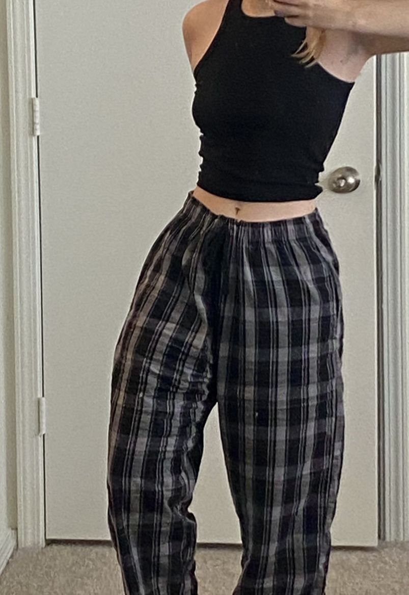 Person wearing a black crop top and black plaid pajama pants indoors.