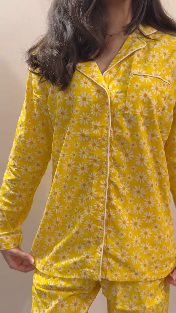 Person wearing yellow pajama set with white daisy floral print and white piping.