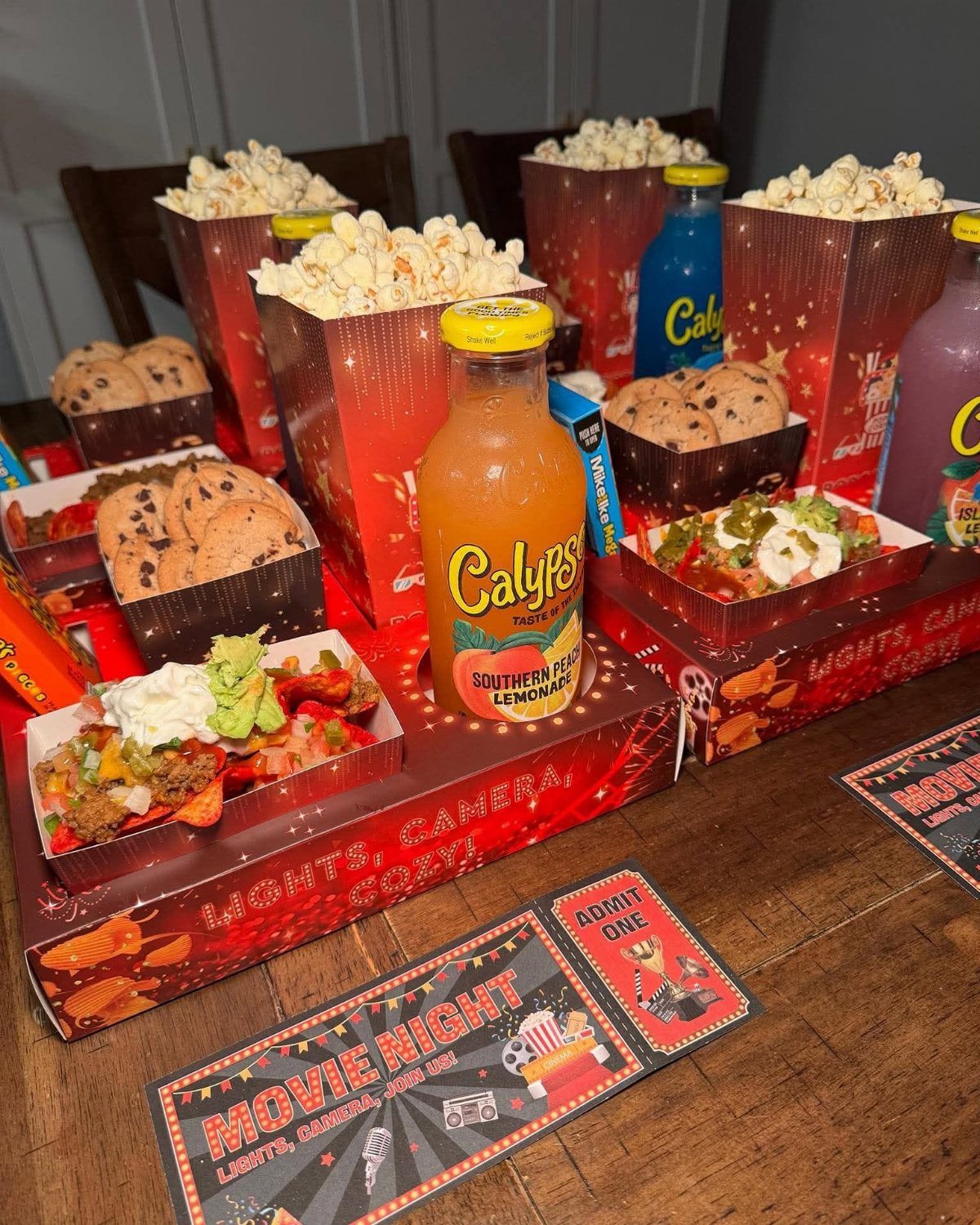 Nachos with guacamole and sour cream alongside popcorn and cookies for movie night.