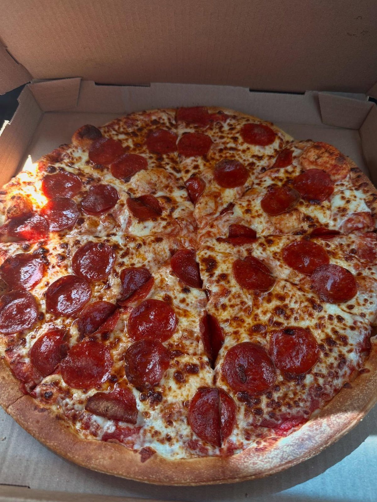 Pepperoni pizza with melted cheese in a cardboard delivery box