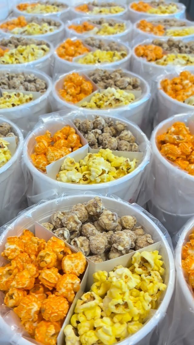 White buckets filled with orange, yellow, and brown popcorn wrapped in plastic.