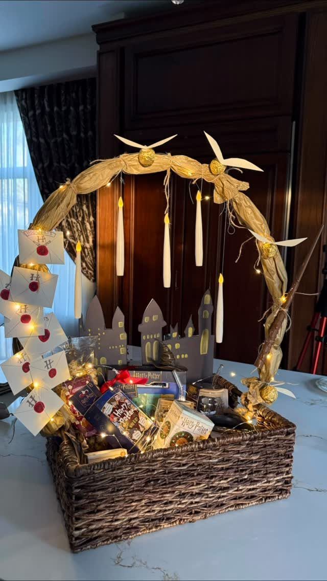 Wicker gift basket filled with snacks and decorated with lights and hanging candles.
