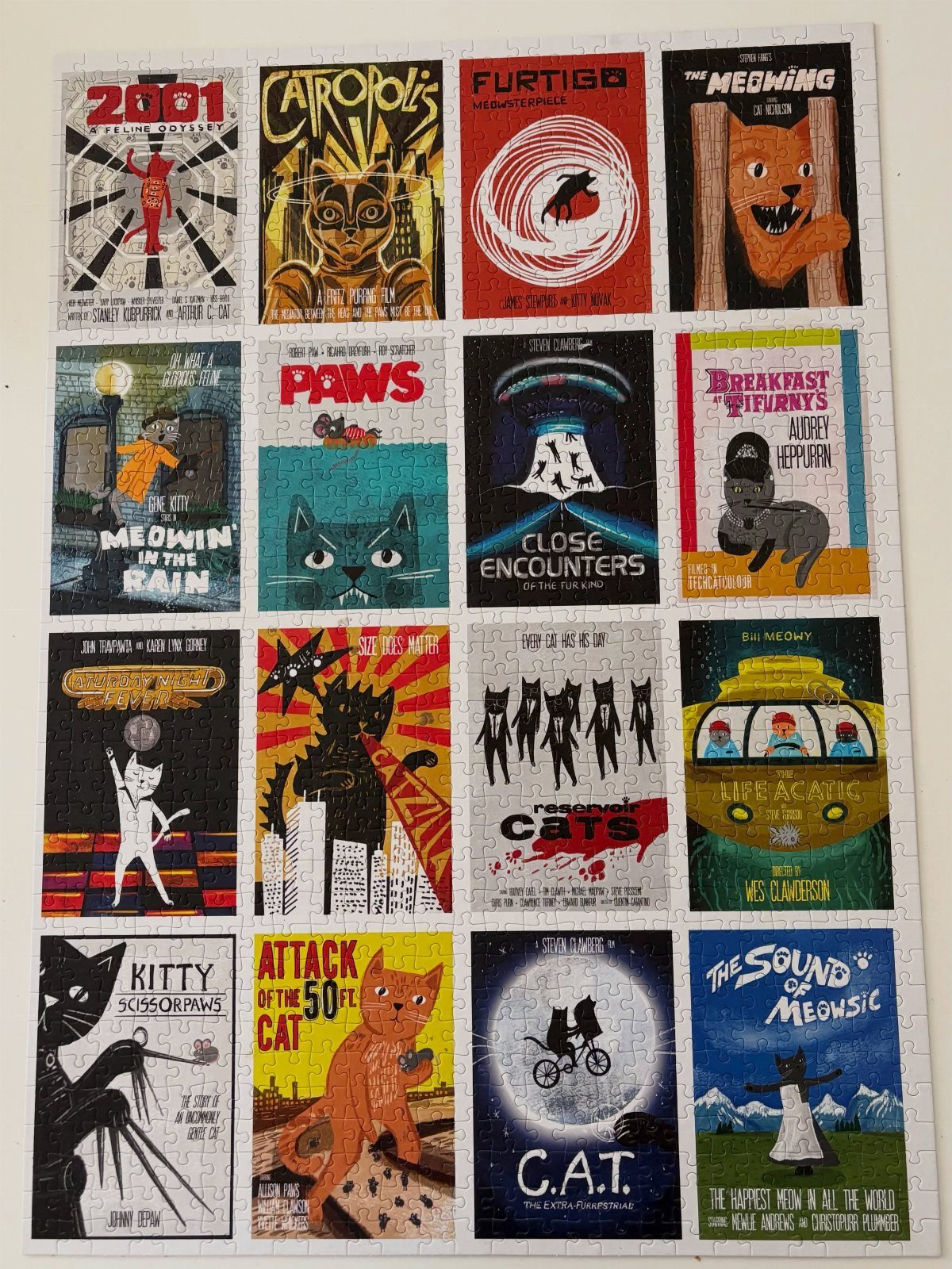 Cat-themed movie poster jigsaw puzzle featuring sixteen humorous feline film parodies.