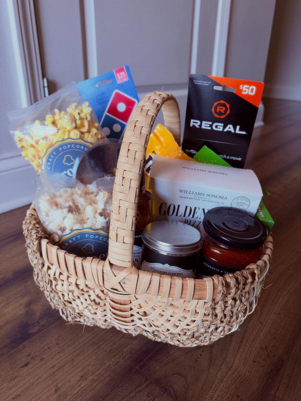 Woven gift basket containing popcorn, a Domino's gift card, and a Regal gift card.
