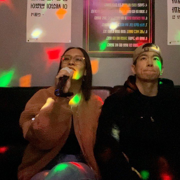 Woman singing into a microphone next to a man in a karaoke room.