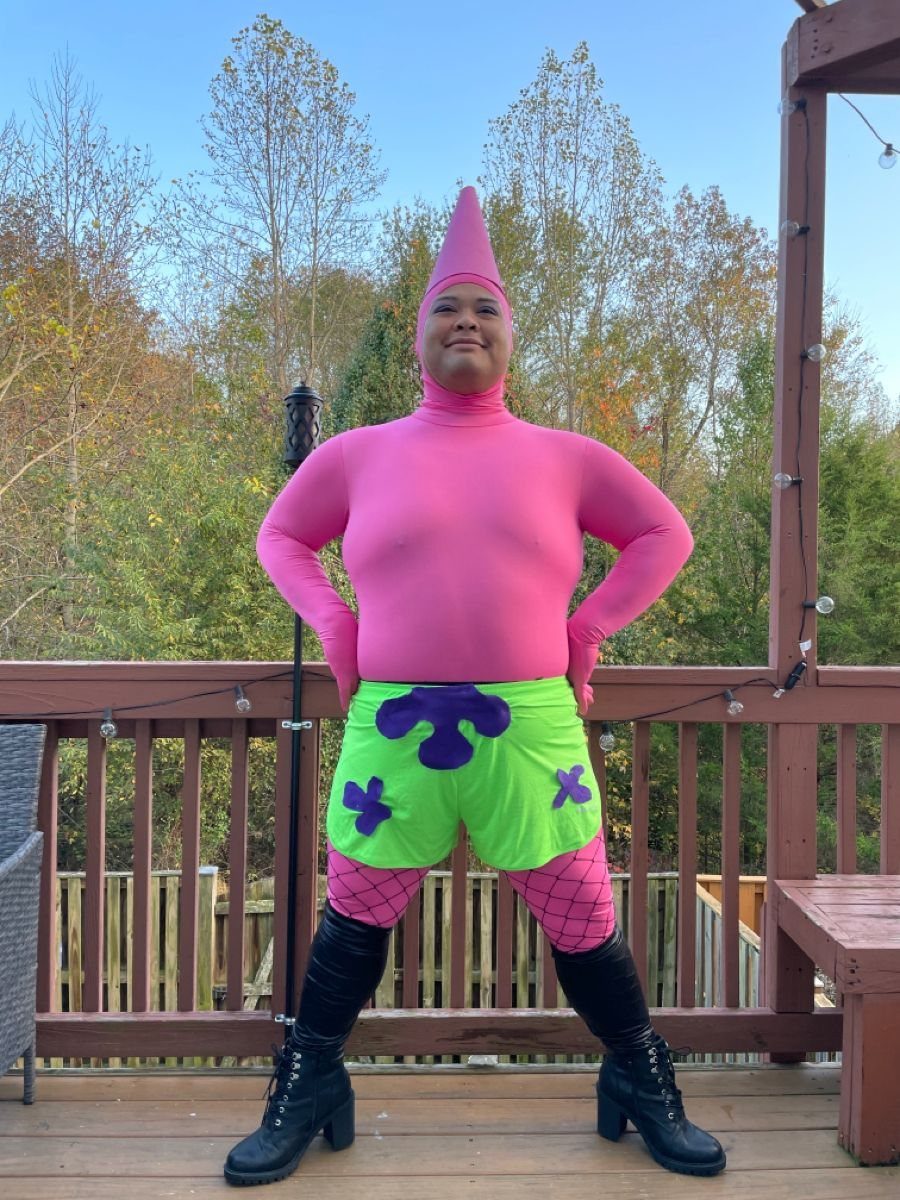 Person in a pink bodysuit, green shorts, and black boots on a deck