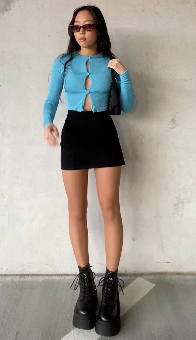 Woman wearing a blue crop top, black mini skirt, and platform boots.