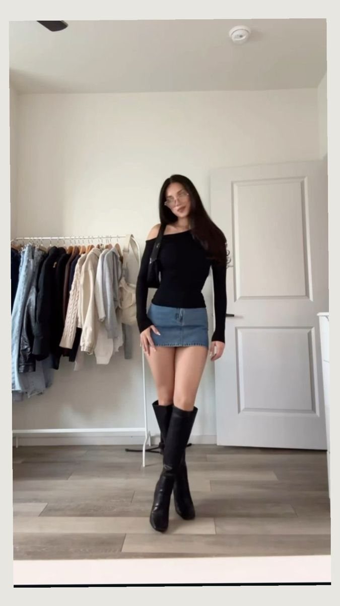Woman wearing a black top, denim mini skirt, and tall black boots.