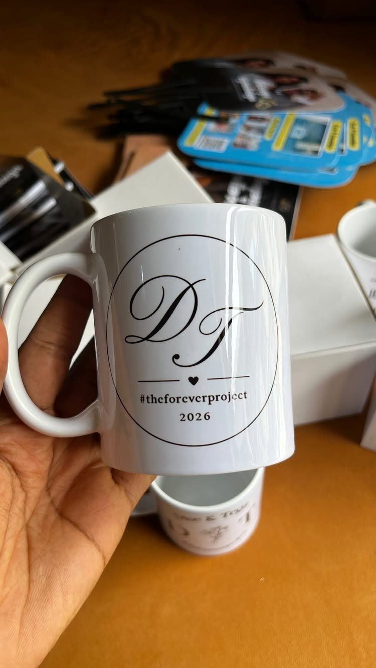 White ceramic mug with a personalized black logo held by a hand.