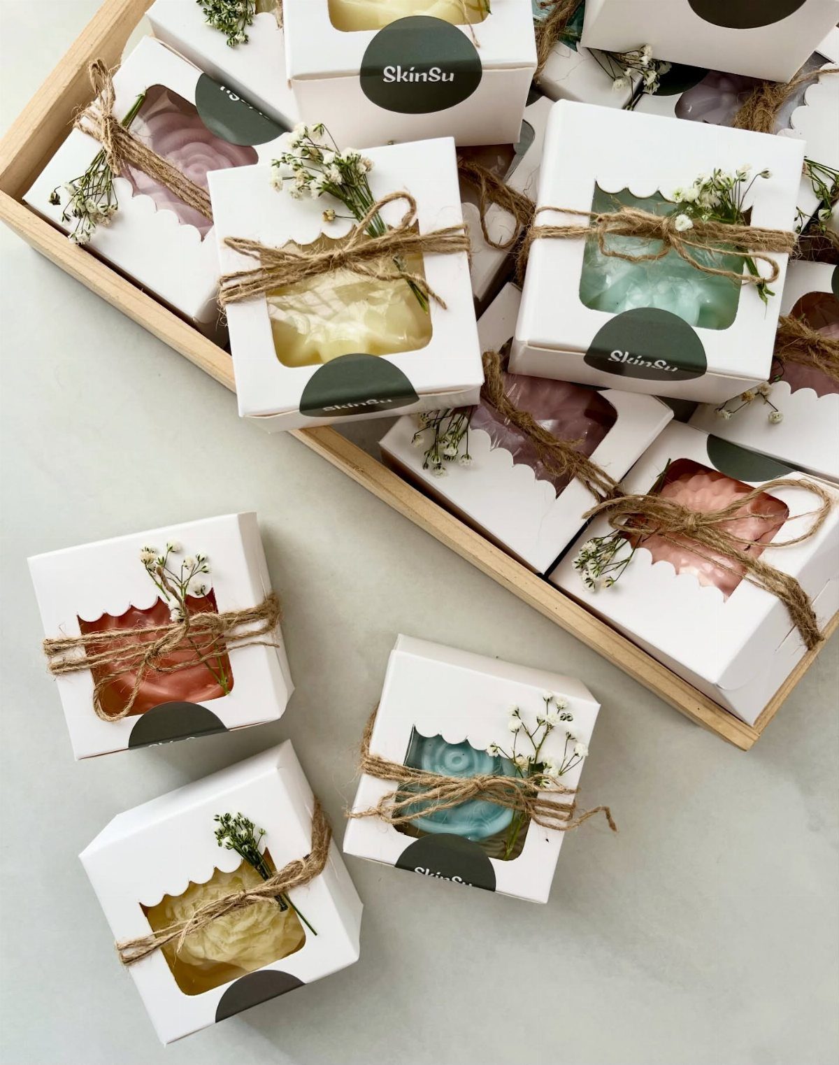 Colorful handmade soap bars in white boxes tied with twine and baby's breath.
