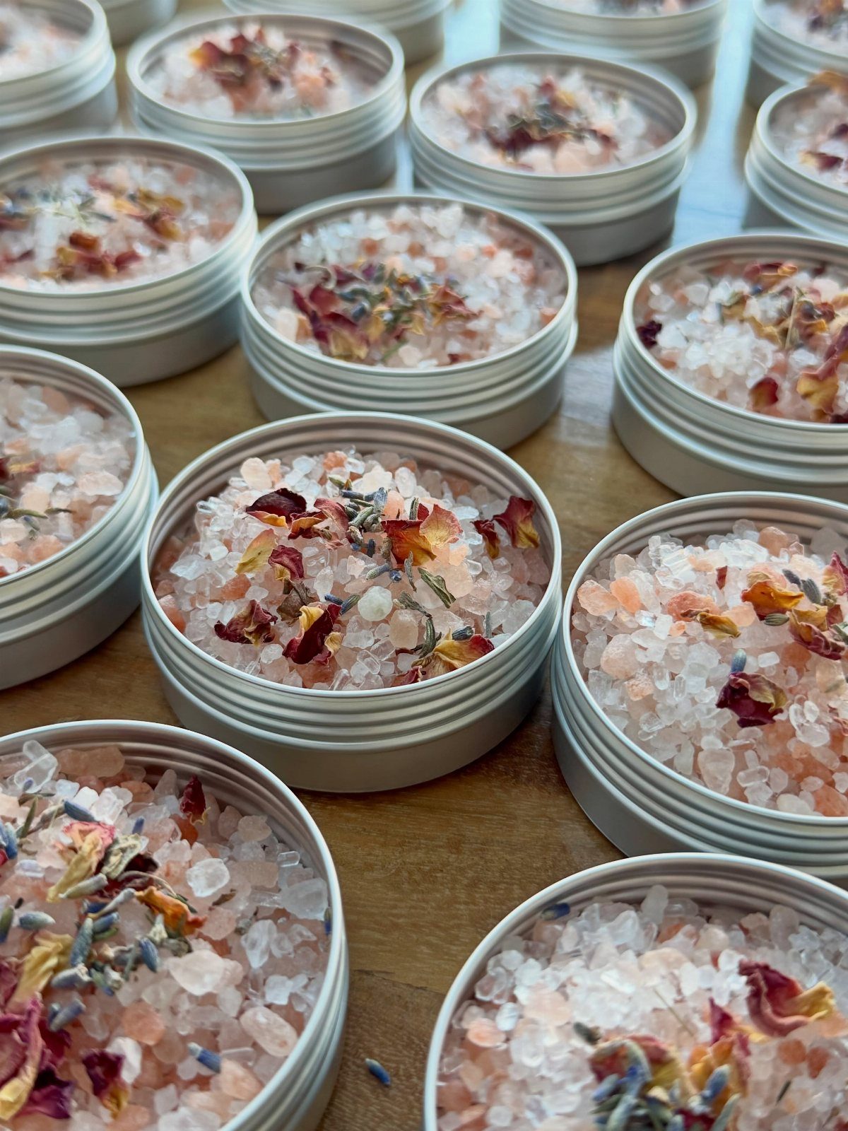 Small silver tins filled with pink bath salts and dried flower petals.
