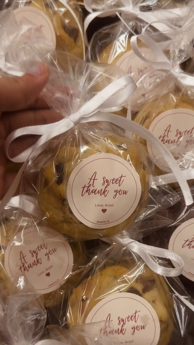 Chocolate chip cookies wrapped in clear bags with white ribbons and thank you labels.