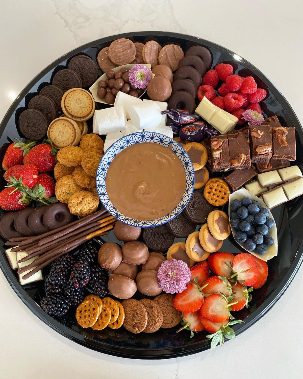 Chocolate fondue platter with melted chocolate, fresh berries, marshmallows, and assorted cookies.