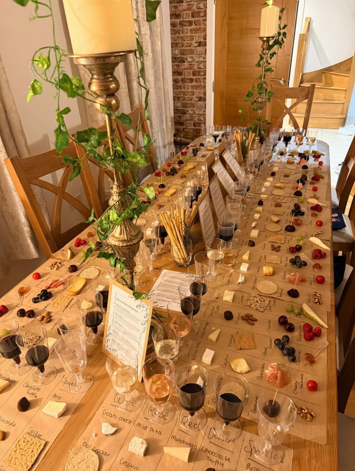 Wine tasting spread with glasses of wine, cheeses, and fruits on parchment paper.