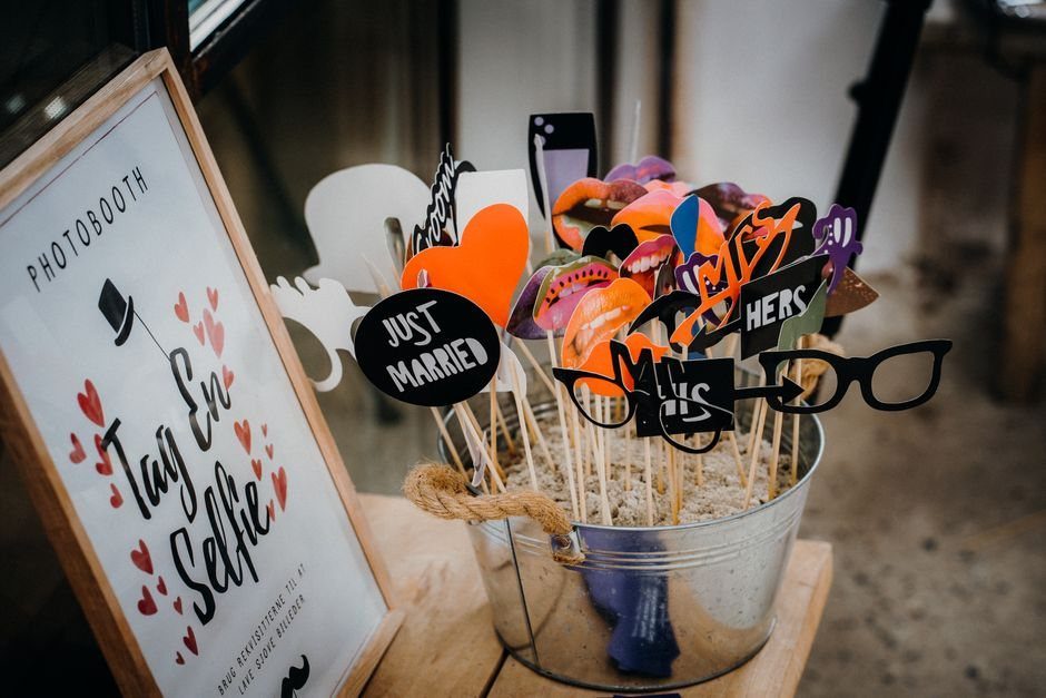 Photo booth props including colorful lips and glasses in a metal bucket