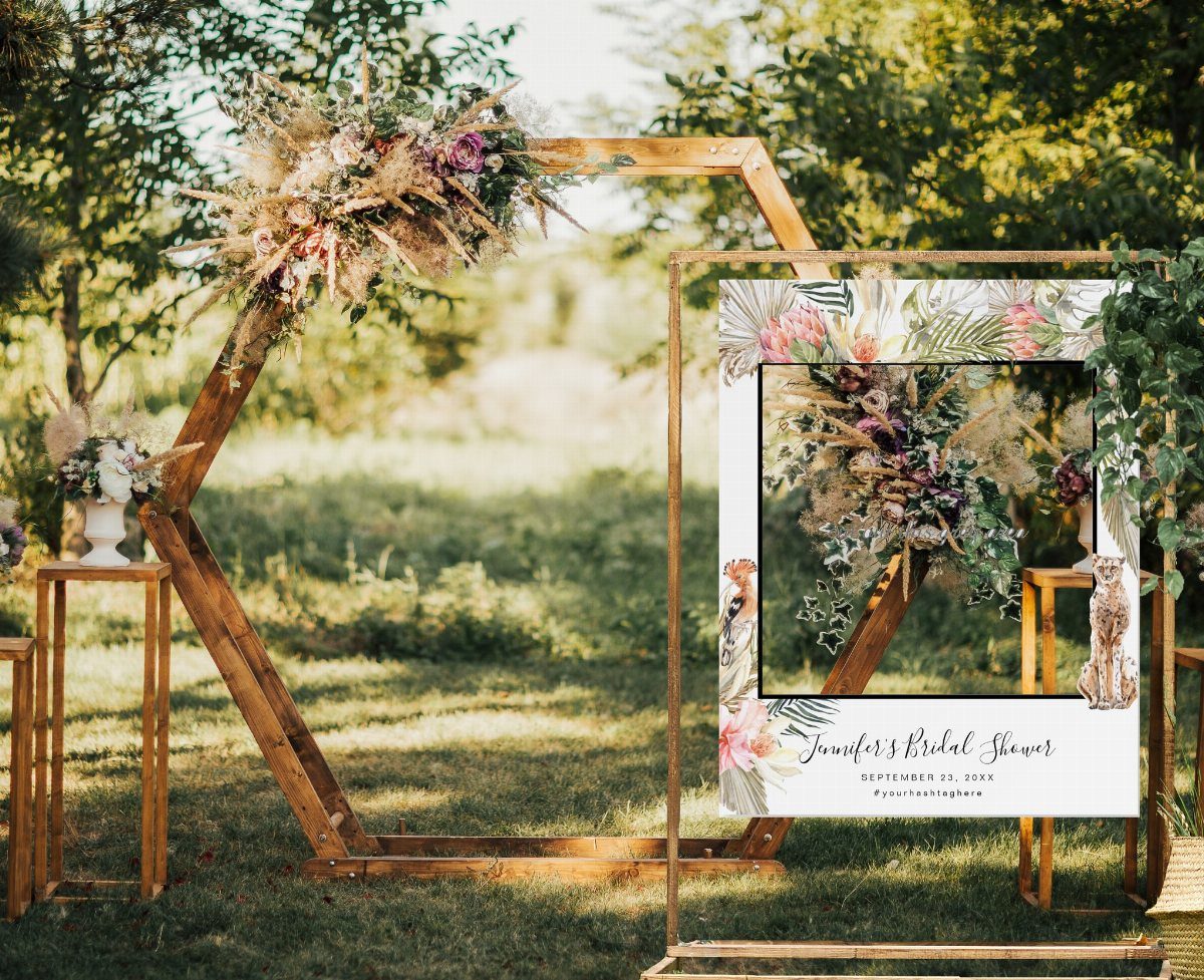 Selfie frame board with floral designs standing next to a wooden hexagonal arch.