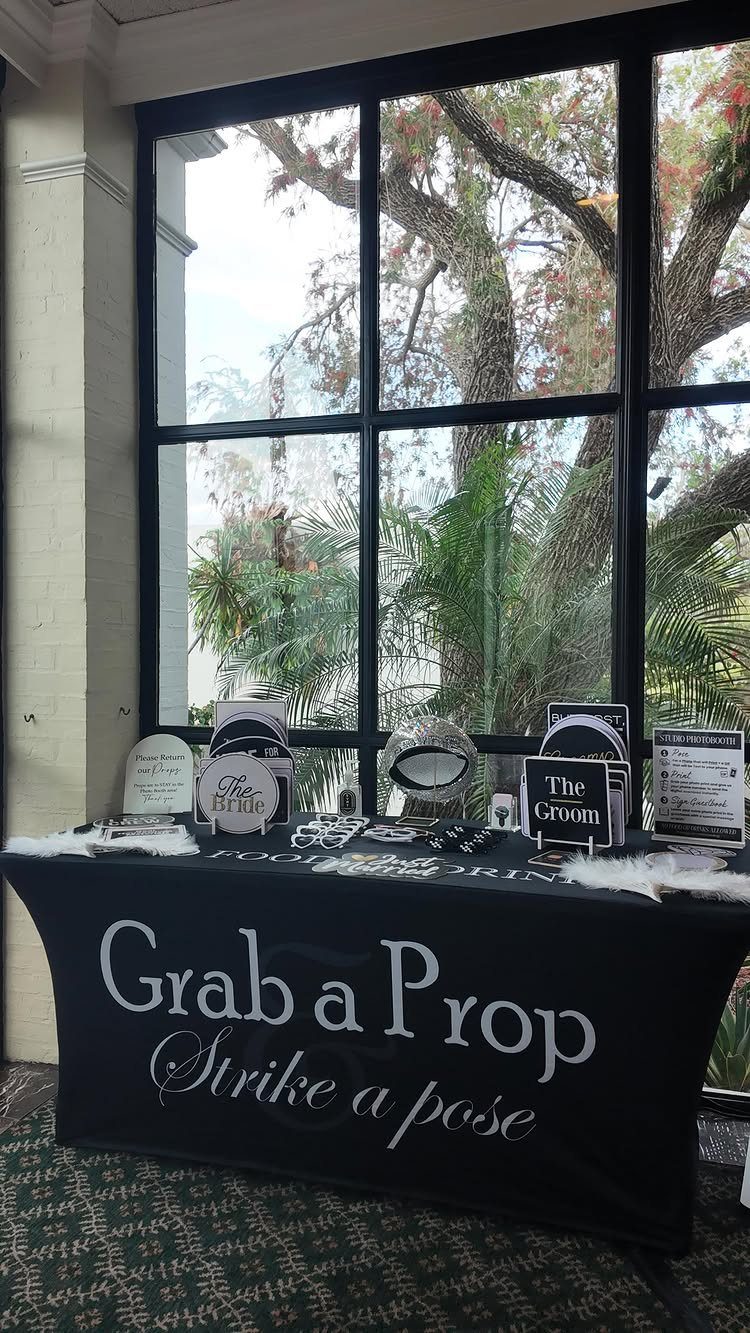 Photo booth prop table with signs and glasses in front of a window