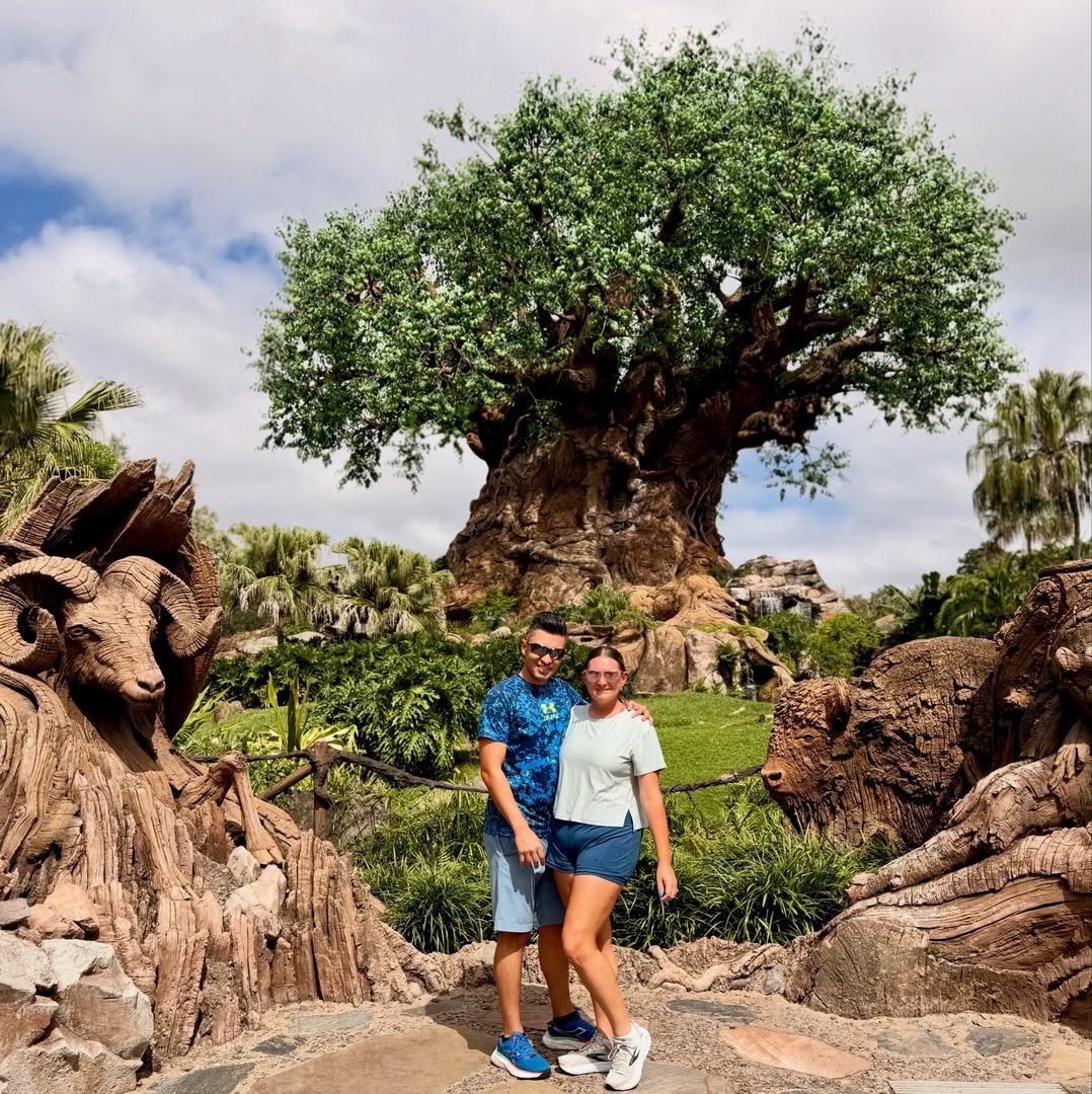 Couple posing in front of the Tree of Life at a theme park.