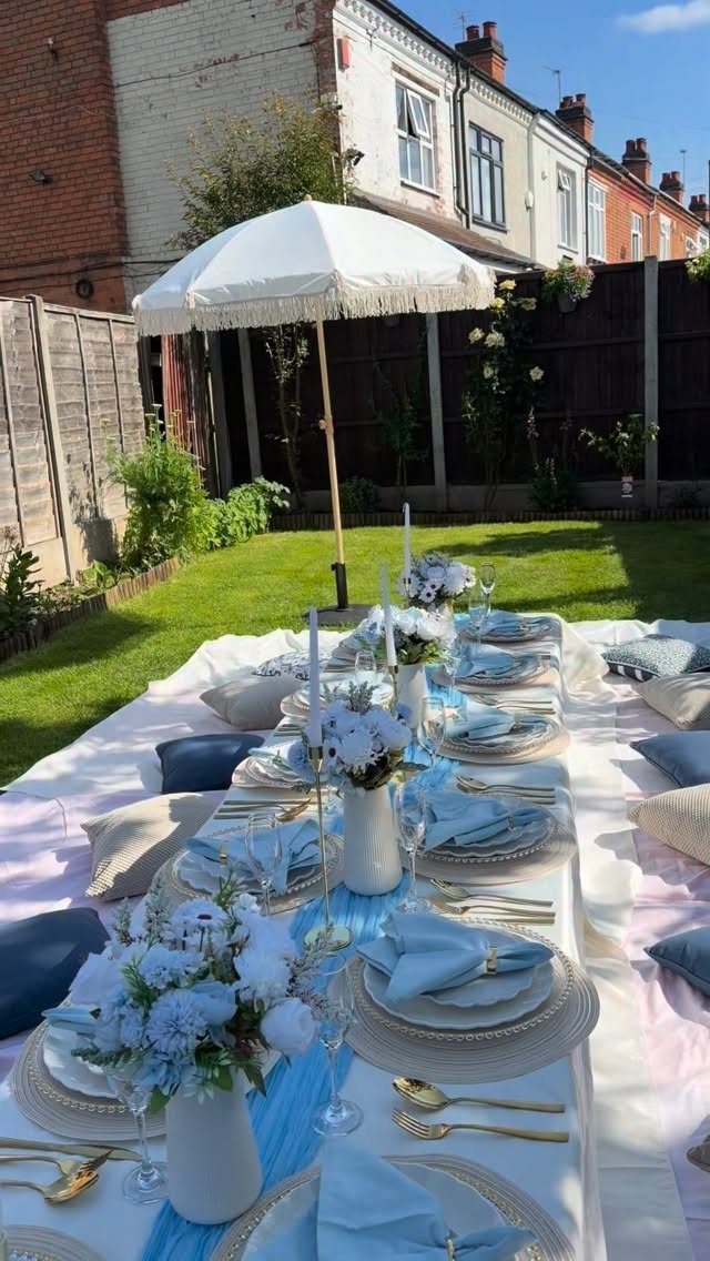 Elegant outdoor table setting with blue and white decor in a residential backyard.