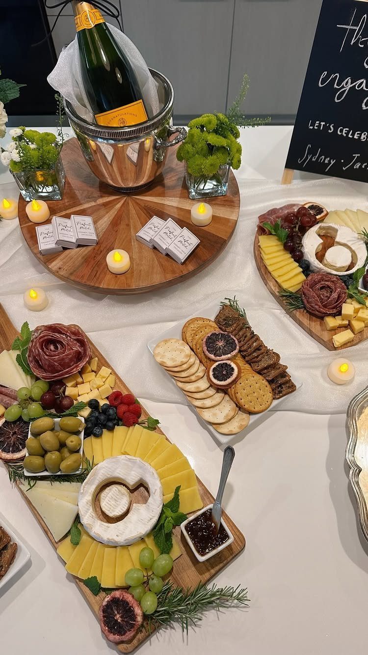 Charcuterie boards and champagne in an ice bucket on a white party table.