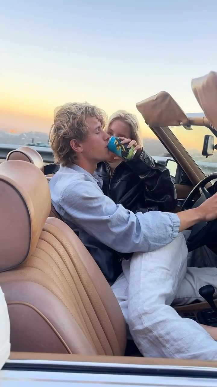 Couple in a vintage convertible car during a sunset drive through the hills.