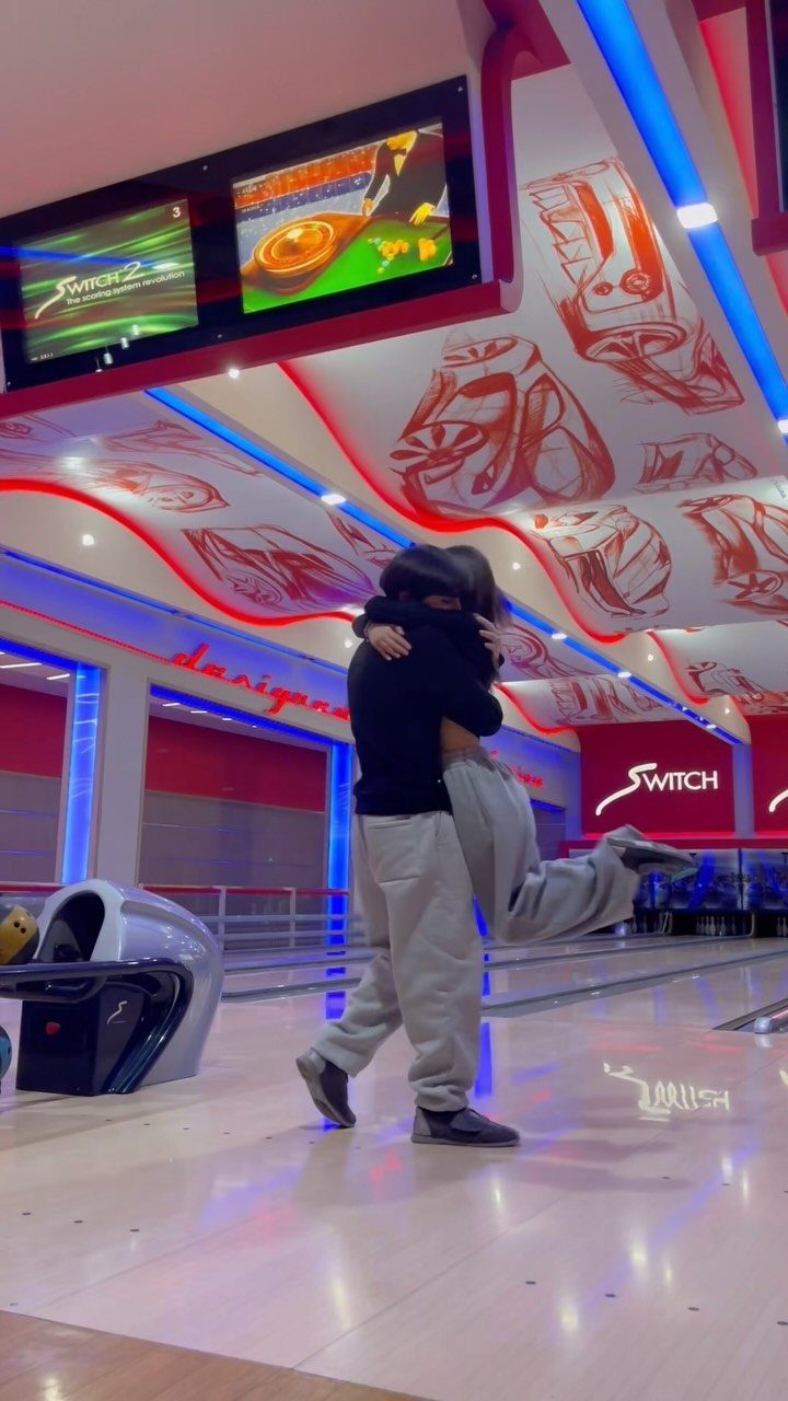 Couple hugging and embracing on a bowling alley lane with neon lighting.