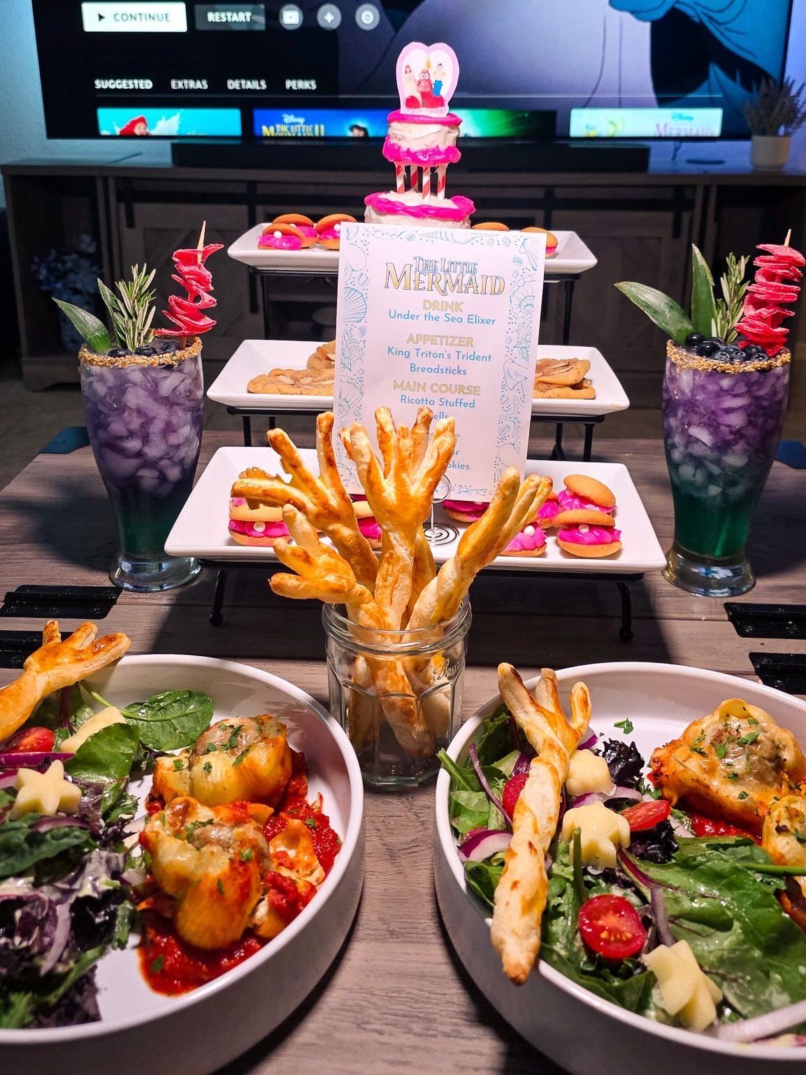 The Little Mermaid themed dinner with seafood plates, purple drinks, and a pink cake.