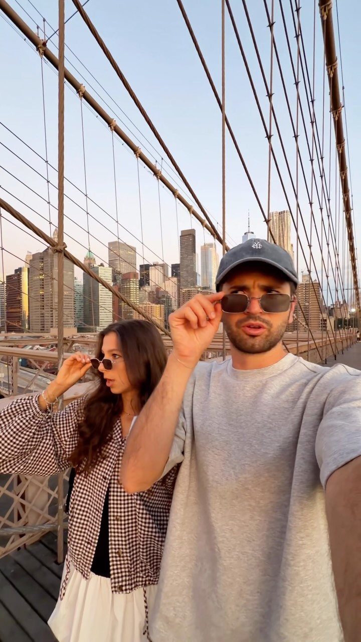 Couple posing for a selfie on the Brooklyn Bridge with NYC skyline background
