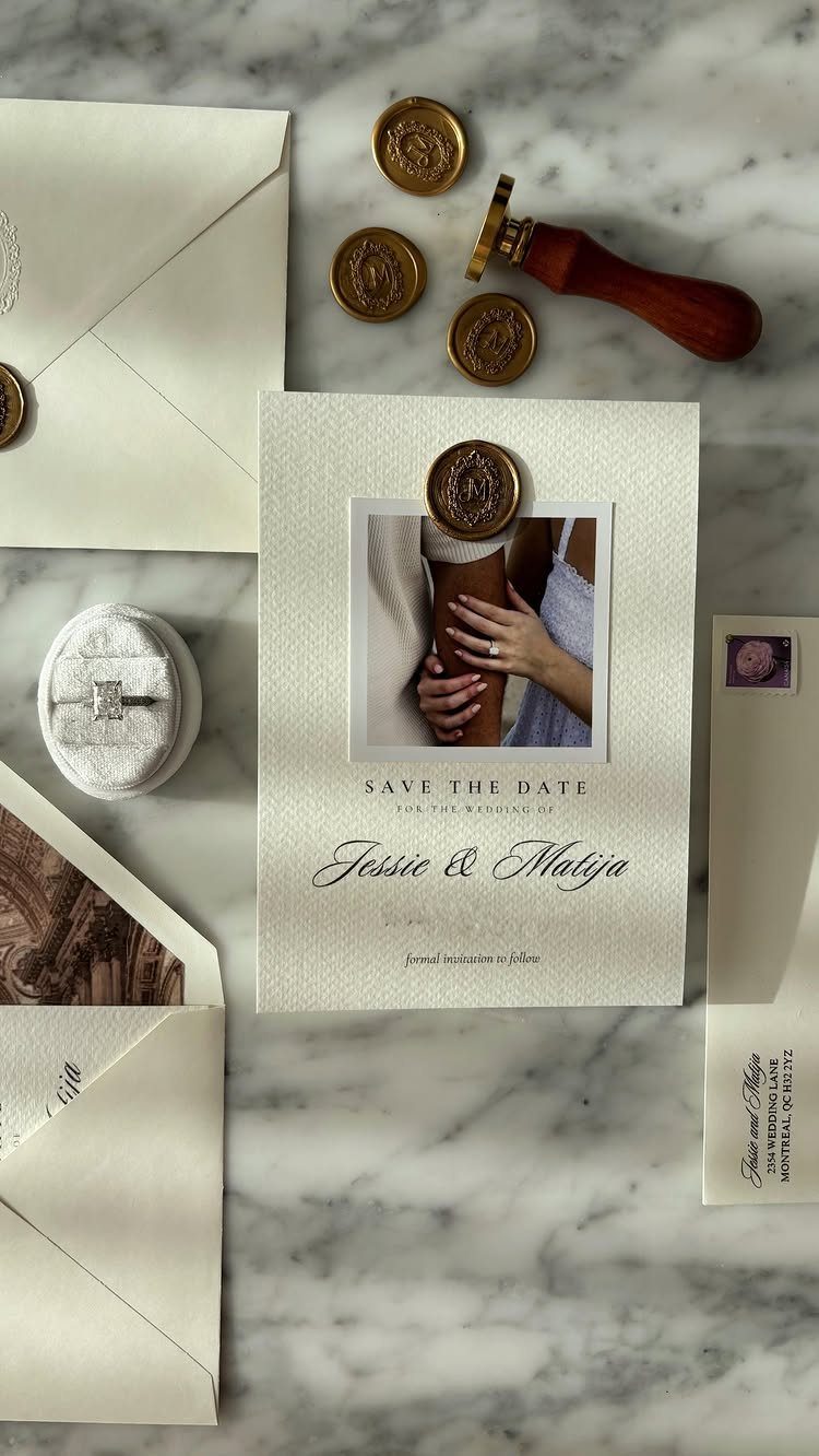 Save the date card with gold wax seal and envelopes on marble surface