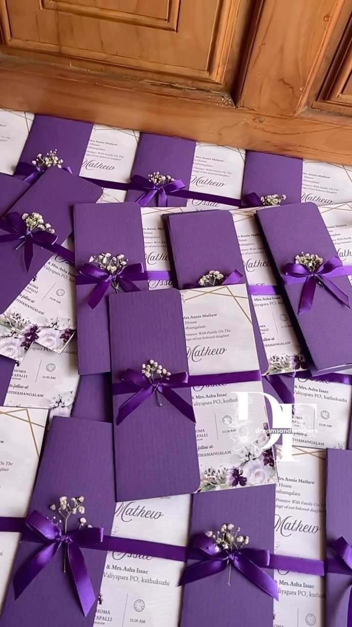 Purple wedding invitations with satin ribbons and small white baby's breath flowers.