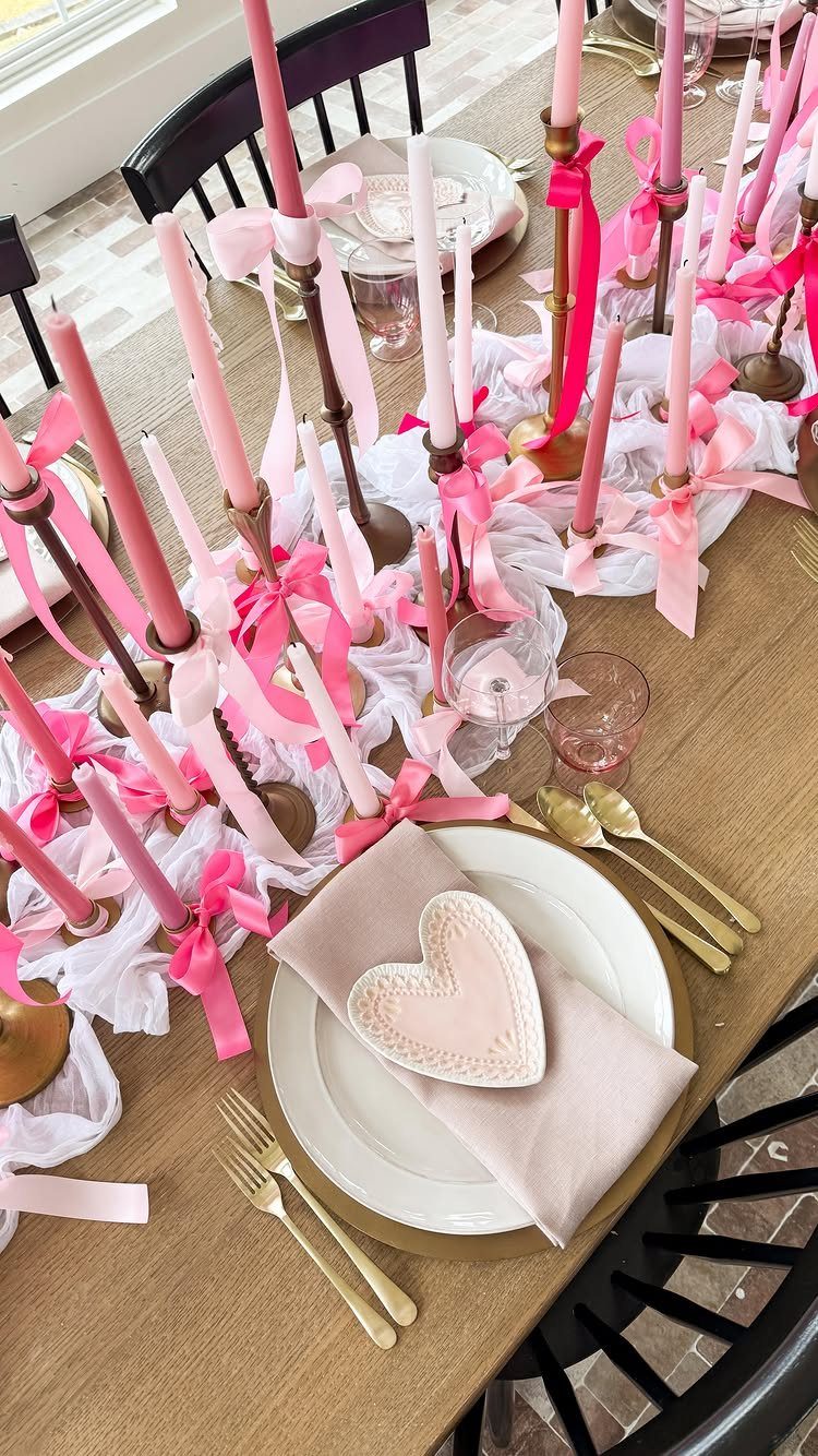 Valentine's Day table setting with pink candles, gold cutlery, and heart-shaped bowls.