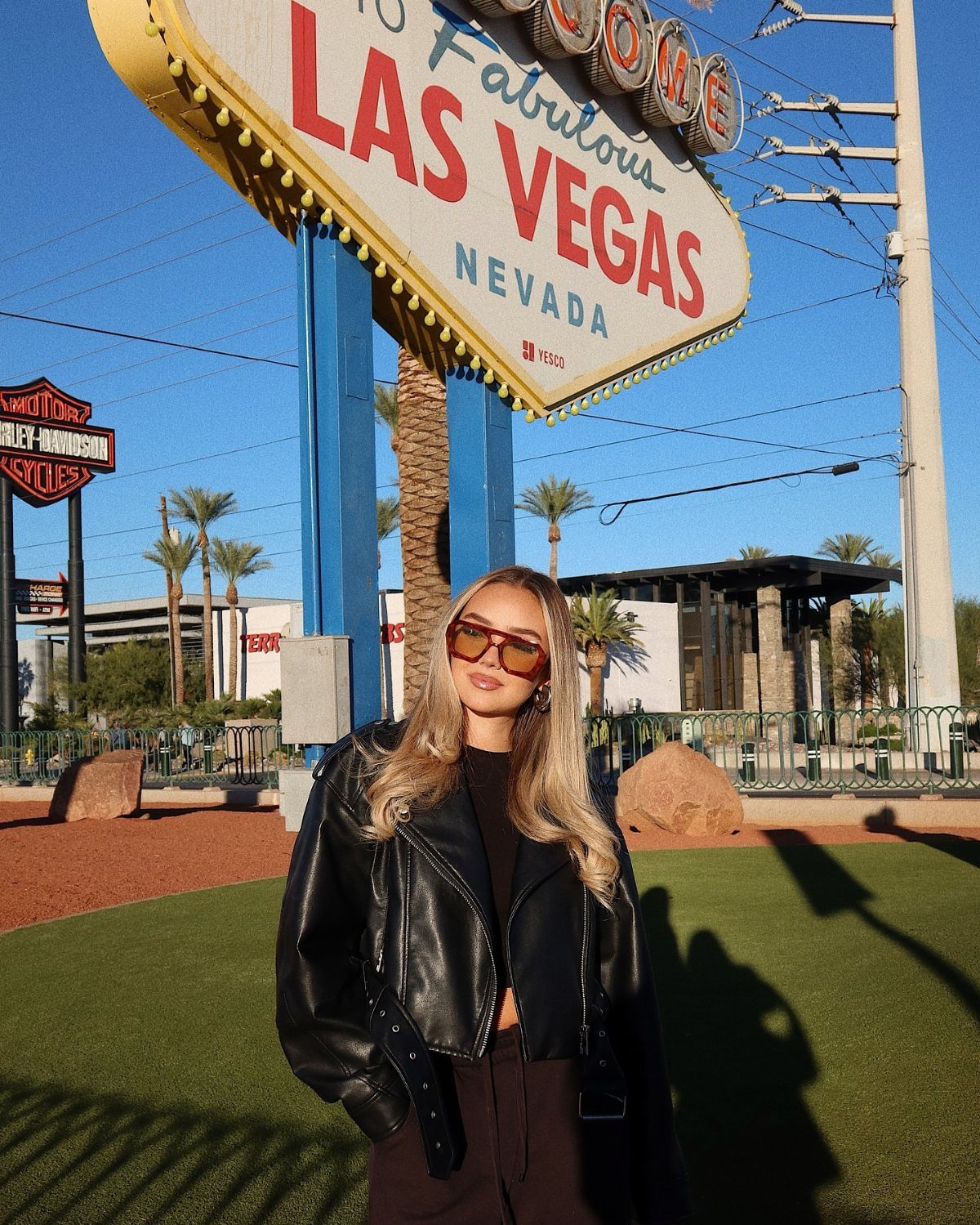 Woman in black leather jacket posing before the Welcome to Fabulous Las Vegas sign