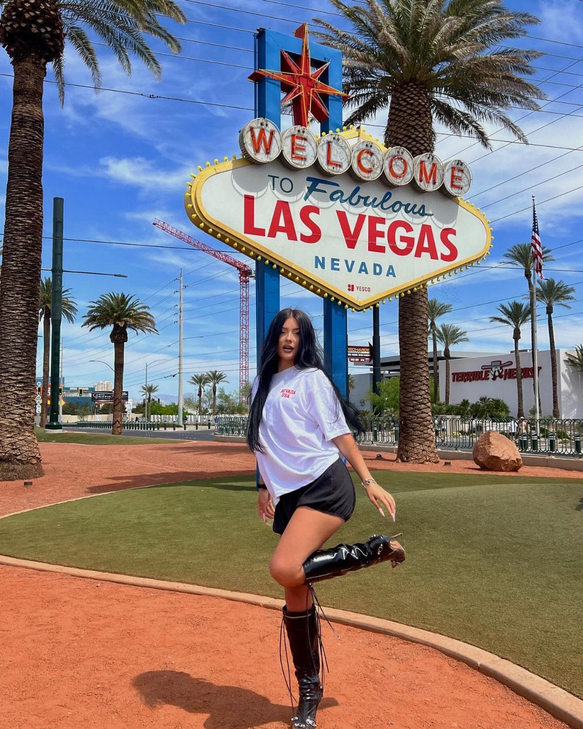 Woman in white t-shirt and black boots posing by Las Vegas sign