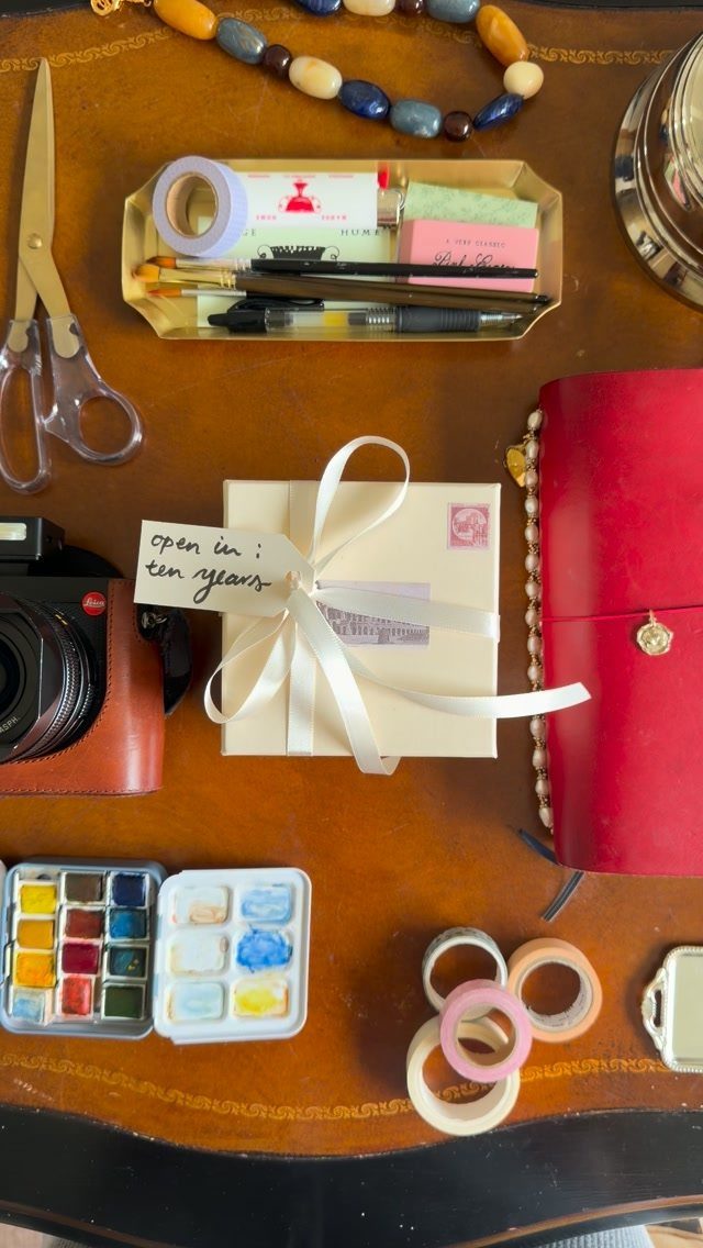 White gift box with a ten year note surrounded by art supplies and camera