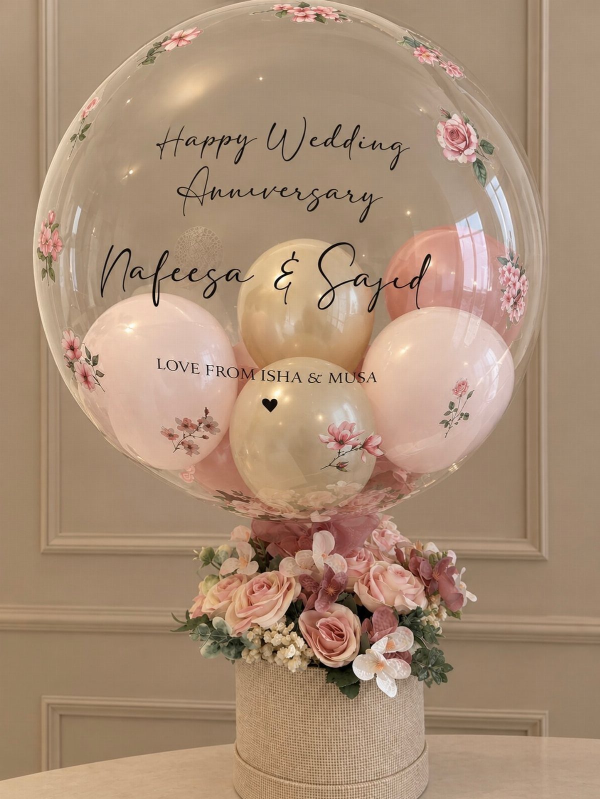 Clear anniversary balloon with smaller balloons inside resting on a box of roses.